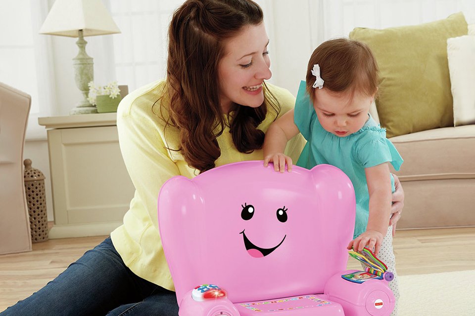 Mum and baby playing around a pink chair.